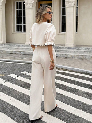 Primer plano del top cropped color crema con cuello Peter Pan y bordado de flores negras.