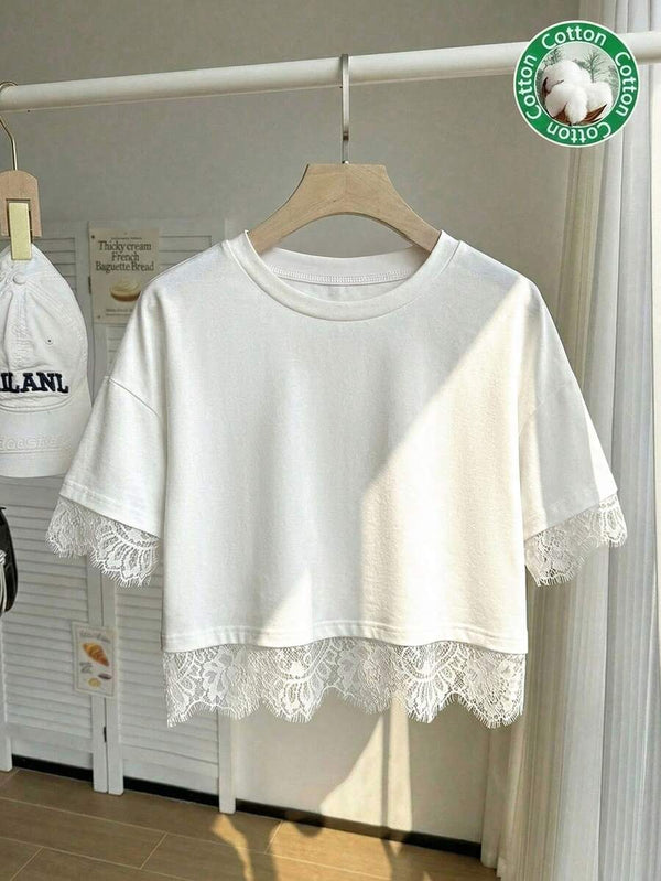 Detalle del cuello redondo y la manga corta con borde de encaje de un top blanco.
