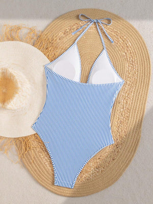 Detalle del escote profundo de un traje de baño a rayas con un dije de estrella de mar dorada.