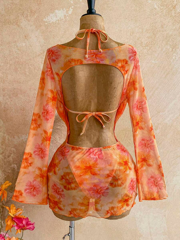 Detalle del top de bikini floral naranja con broche metálico dorado y collar.