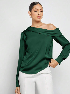 Detalle de la manga larga y el puño de la blusa elegante de satén verde oscuro.