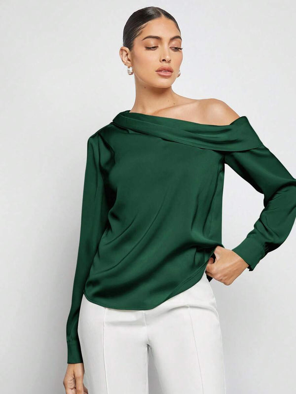 Detalle de la manga larga y el puño de la blusa elegante de satén verde oscuro.