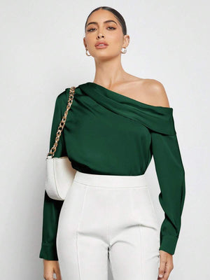 Modelo luciendo una blusa asimétrica verde combinada con un pantalón blanco de talle alto.