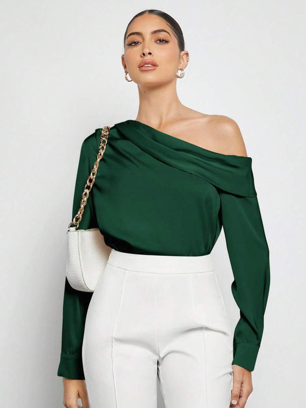 Modelo luciendo una blusa asimétrica verde combinada con un pantalón blanco de talle alto.