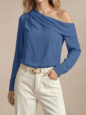 Primer plano del escote asimétrico drapeado de una blusa azul de manga larga.