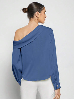 Mujer modelando una blusa asimétrica de hombro descubierto mostrando su ajuste suelto.