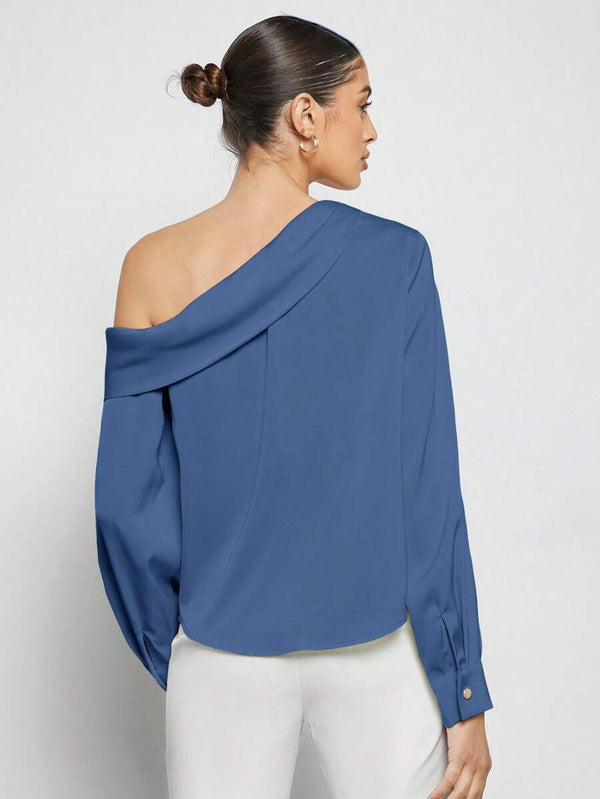 Mujer modelando una blusa asimétrica de hombro descubierto mostrando su ajuste suelto.