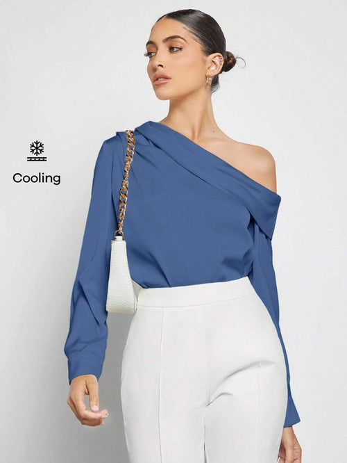 Vista frontal de una mujer usando una blusa azul asimétrica de un solo hombro con pantalones blancos.