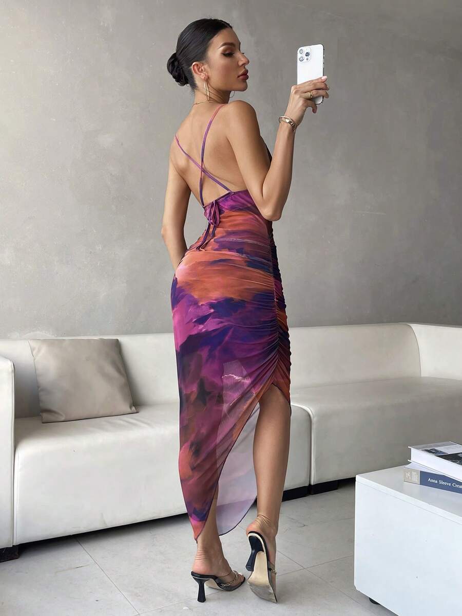 Vista frontal de una mujer luciendo un vestido midi ajustado con estampado tie-dye en tonos morados y naranjas.