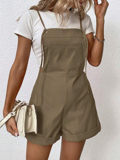 Mujer vistiendo un overall corto color marrón caqui sobre una camiseta blanca, sosteniendo un bolso blanco.