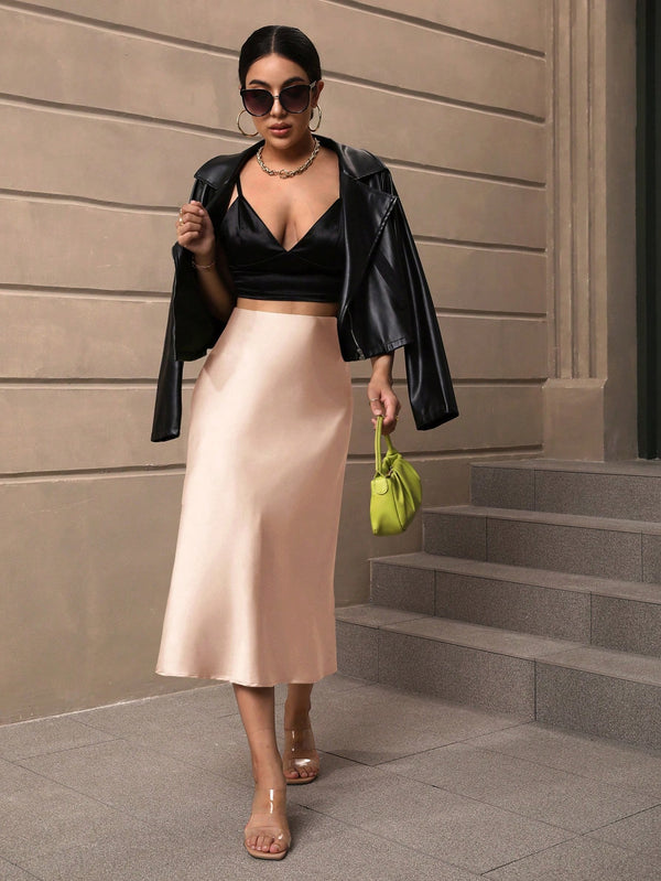 Falda albaricoque combinada con top negro y chaqueta.