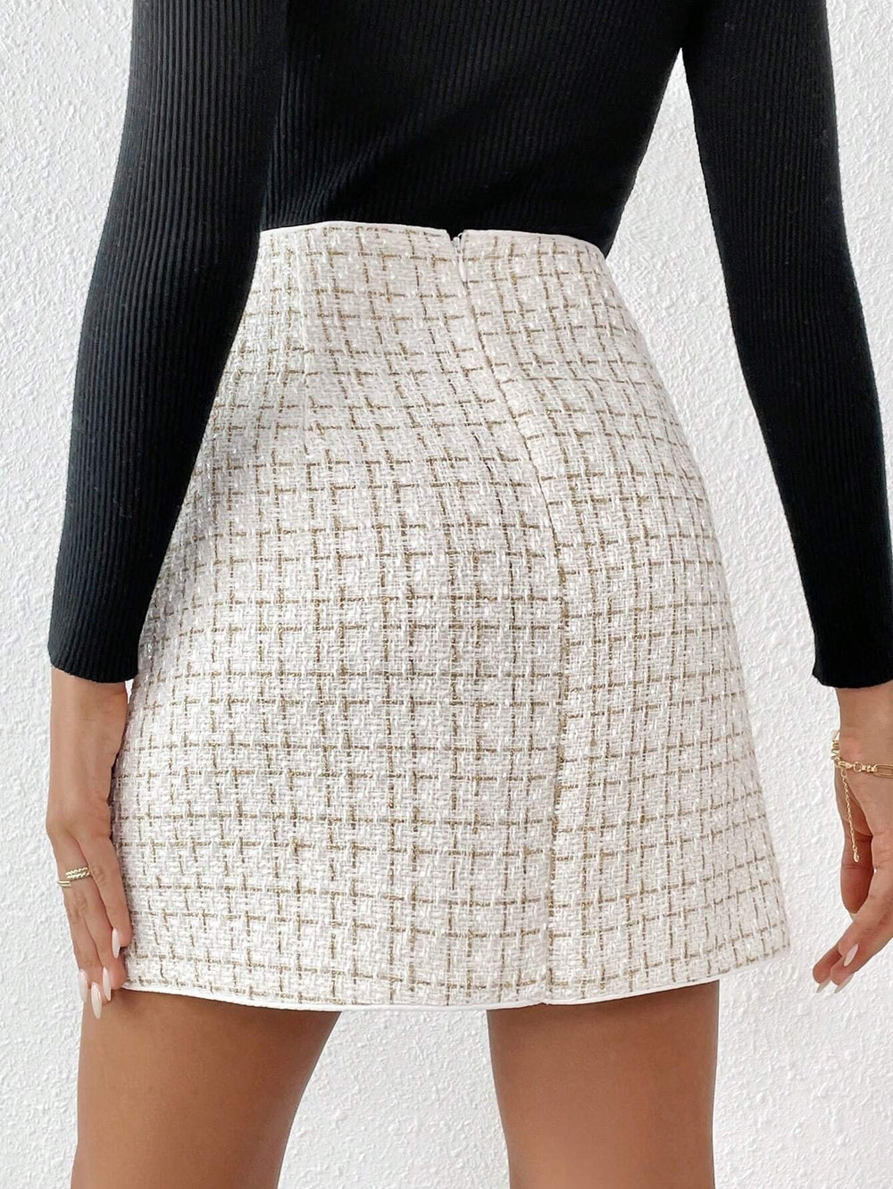 Vista frontal de la falda corta elegante con botonadura doble y estampado a cuadros.