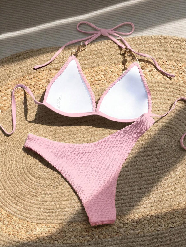 Detalle del top de bikini rosa con tirante de perla y aro dorado.