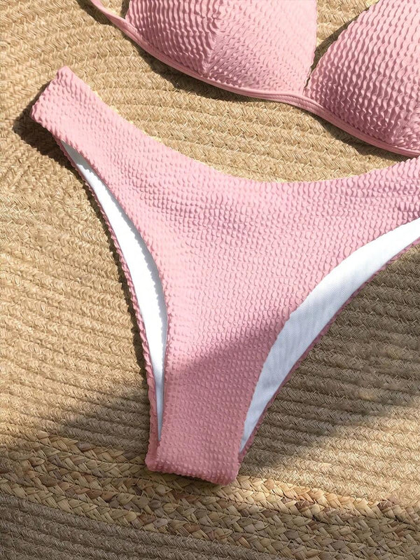 Primer plano de la braguita de bikini rosa de corte alto y tejido texturizado.
