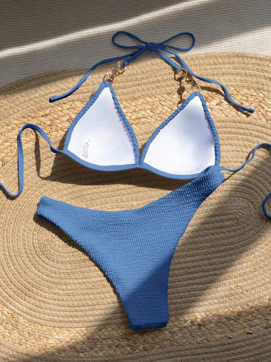 Bikini azul de dos piezas texturizado con detalles de perlas en los tirantes, visto desde arriba.