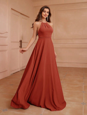 Mujer de espaldas mostrando el diseño completo de un vestido largo terracota ideal para eventos formales.