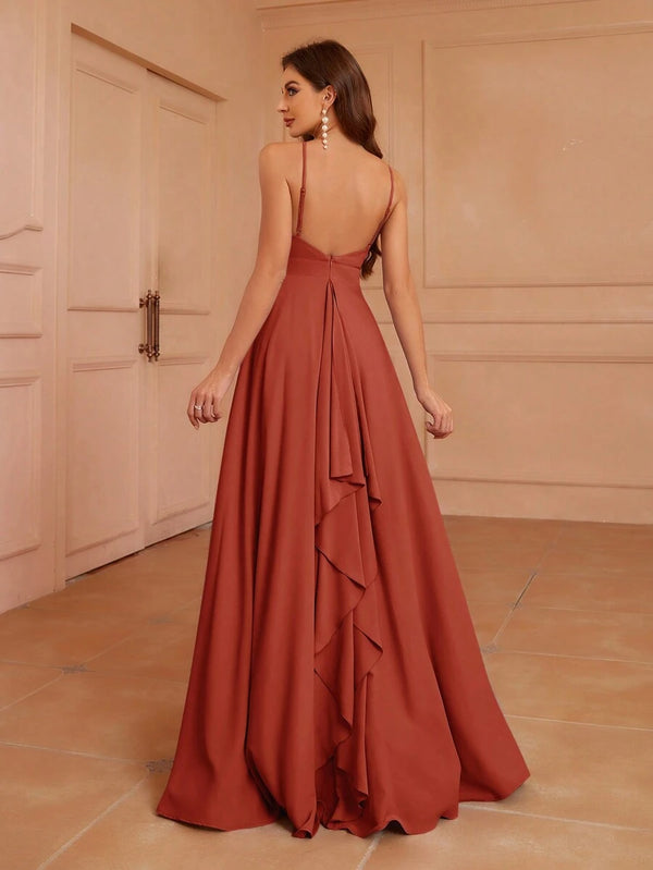 Vista trasera de una mujer luciendo un vestido largo de fiesta color terracota con espalda abierta y detalle de volantes.
