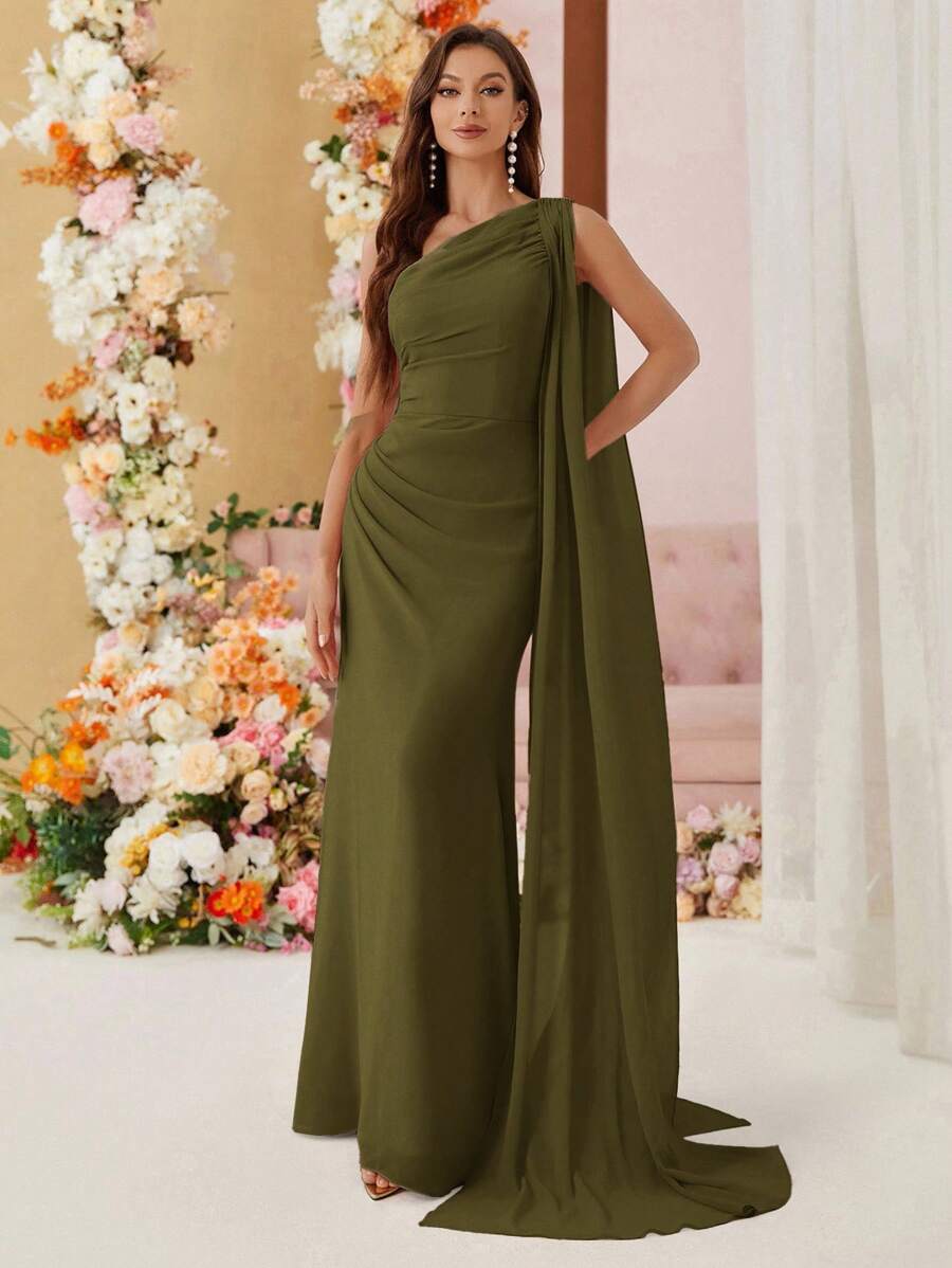 Mujer modelando un jumpsuit elegante verde militar de un hombro con capa larga y detalle fruncido.