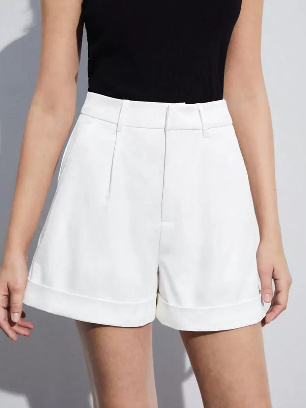 Primer plano de una mujer usando shorts blancos de vestir y un top negro ajustado.