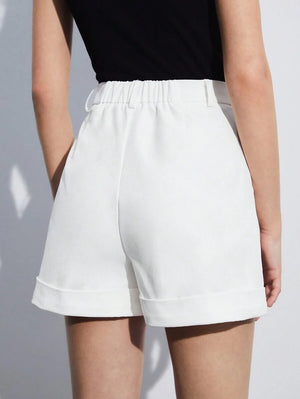 Vista inferior de una modelo luciendo shorts blancos de pierna recta y sandalias de tacón negras.