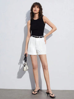 Modelo de cuerpo completo vistiendo shorts blancos de talle alto y un top negro sin mangas.