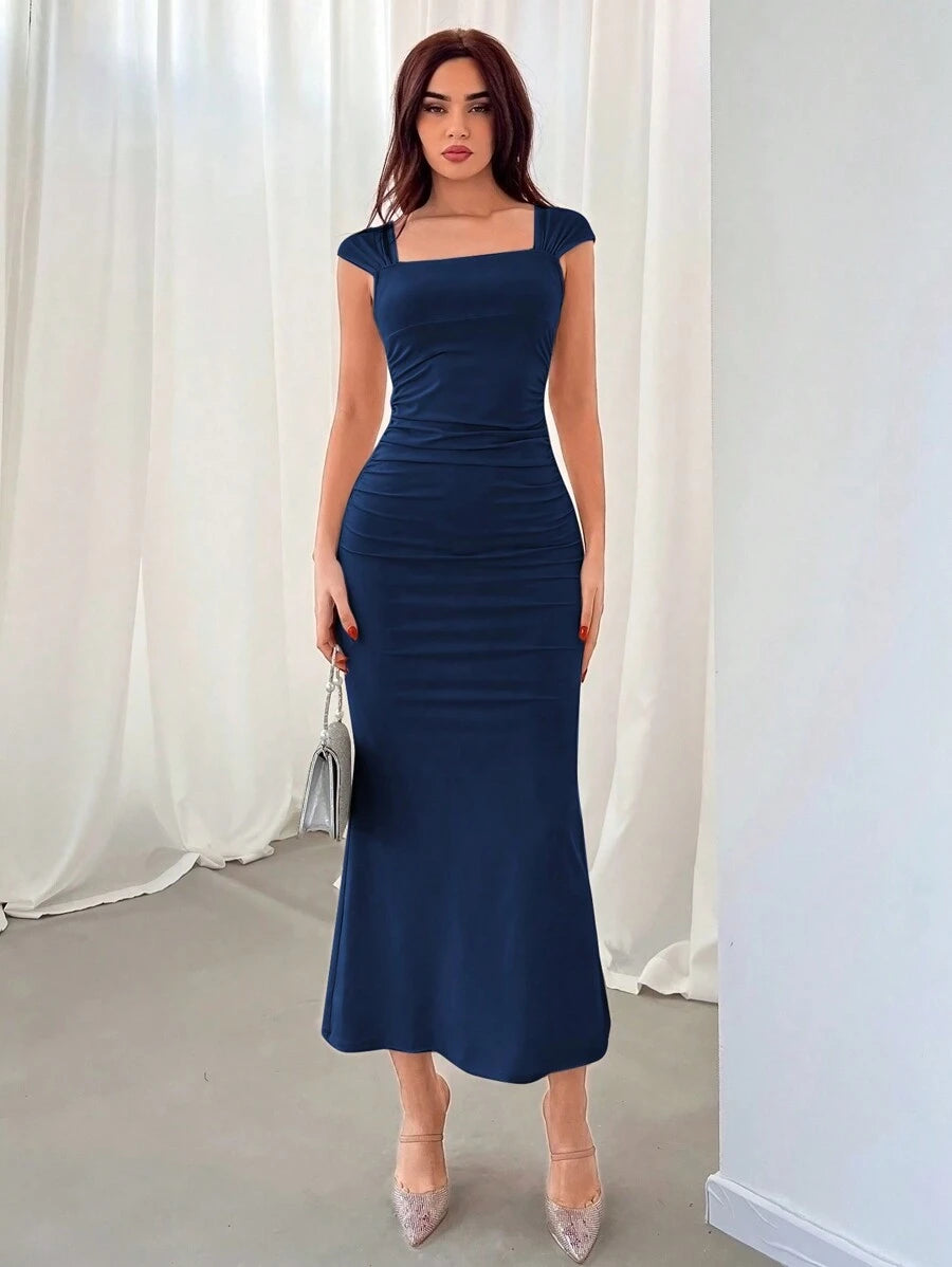 Mujer posando con un vestido midi azul marino de escote cuadrado y mangas casquillo.
