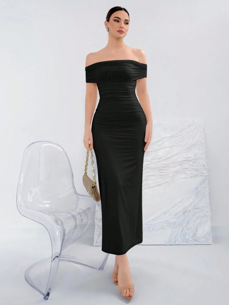 Vista frontal de una mujer usando un vestido negro largo elegante con hombros descubiertos.
