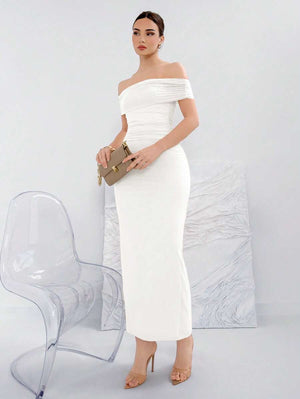 Detalle de la parte inferior de un vestido blanco midi y sandalias nude.
