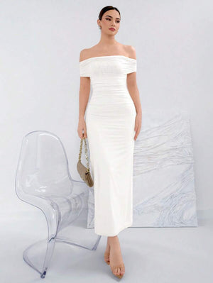 Mujer modelando un vestido blanco largo de hombros descubiertos con detalle fruncido.