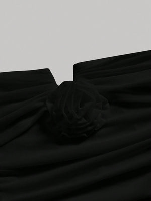 Detalle del escote con flor en el vestido negro elegante.
