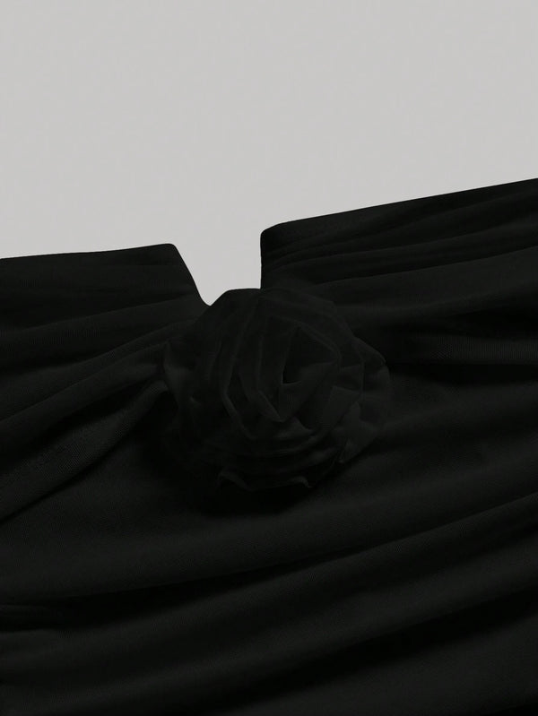 Detalle del escote con flor en el vestido negro elegante.