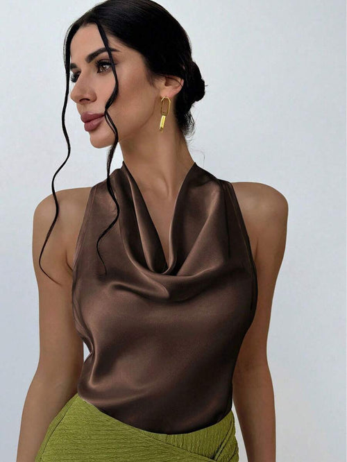 Mujer de perfil luciendo un top satinado café con cuello caído y aretes dorados.