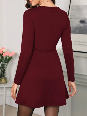 Vestido elegante burdeos de manga larga – detalle cintura y bolsillos.