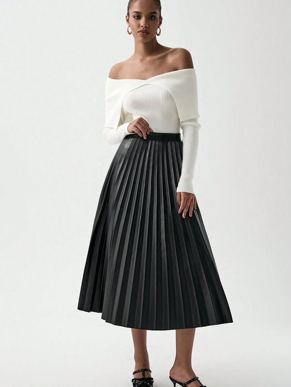 Modelo luciendo falda negra plisada con blusa blanca elegante.