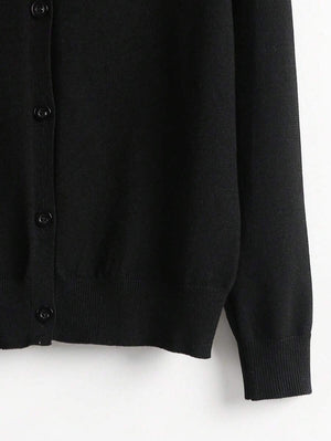 Detalle inferior del cardigan negro básico con terminación acanalada.