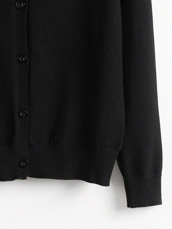 Detalle inferior del cardigan negro básico con terminación acanalada.