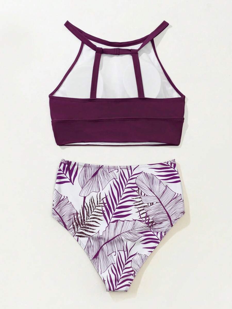 Vista frontal de bikini de dos piezas con top morado de cuello alto y braguita blanca de talle alto con estampado de hojas tropicales.