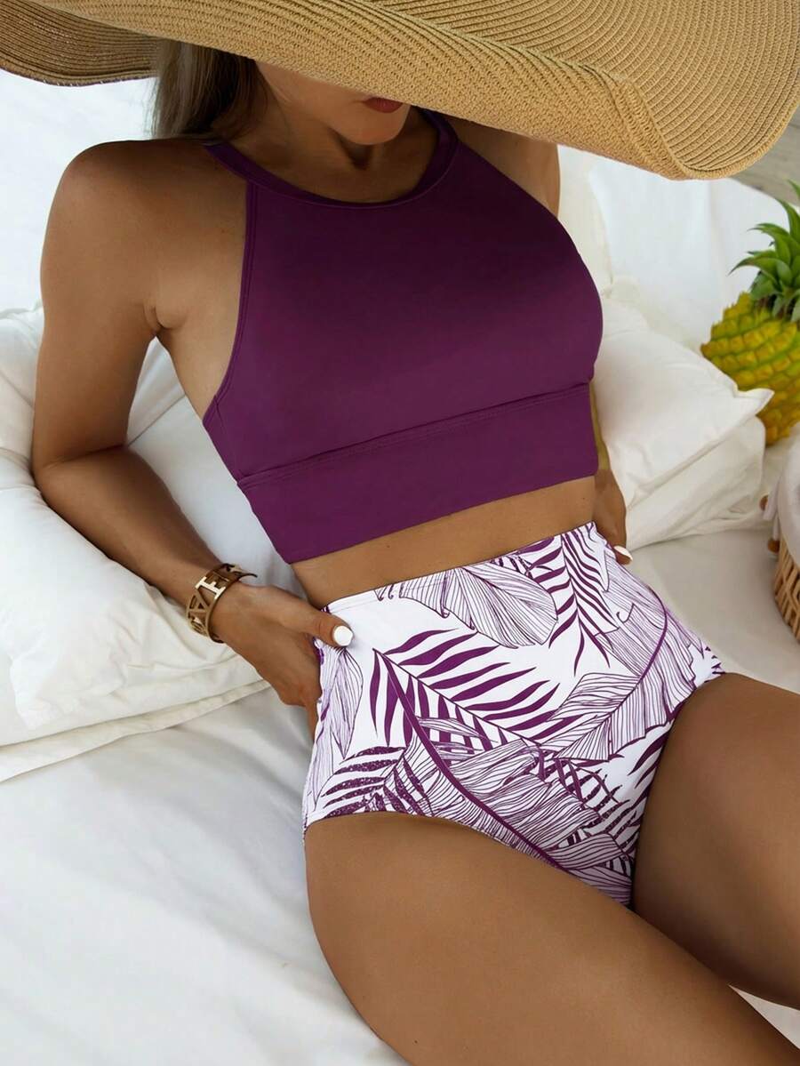 Vista frontal de bikini de dos piezas con top morado de cuello alto y braguita blanca de talle alto con estampado de hojas tropicales.