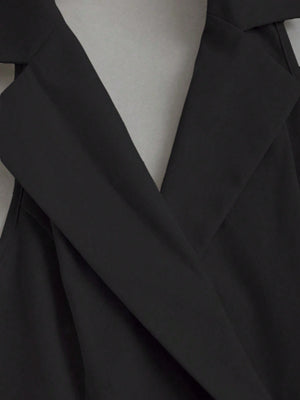 Detalle del cuello solapa del vestido corto negro con solapa y plisado.