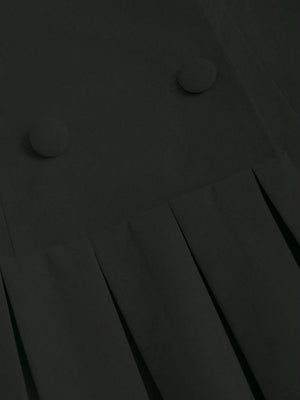 Detalle del plisado y doble botonadura del vestido corto negro con solapa y plisado.