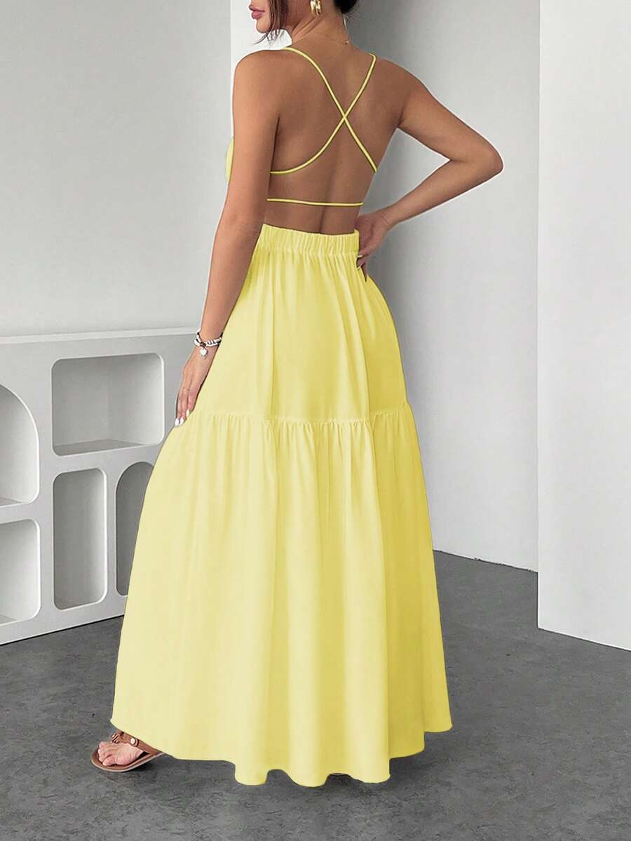 Mujer luciendo un vestido largo amarillo vibrante con tirantes finos y falda de volantes.