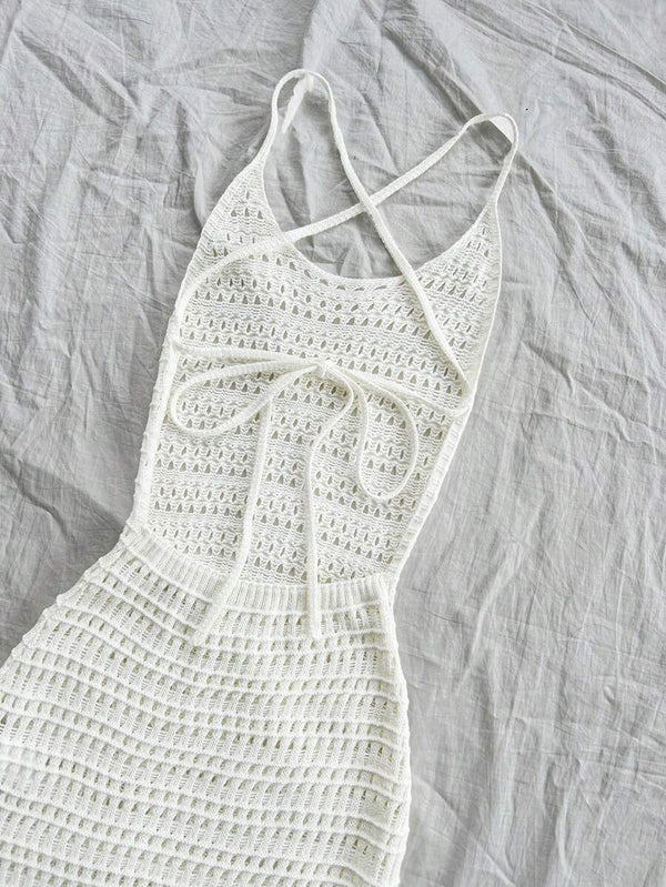 Primer plano de la textura calada de un vestido largo de tejido tipo crochet color blanco.
