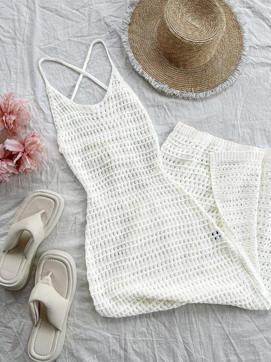 Vestido largo tejido de crochet blanco en un flat lay con sandalias, sombrero de paja y flores.