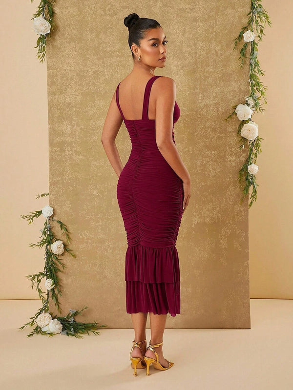 Detalle del bajo de un vestido midi color vino tinto mostrando la falda con volantes en dos capas y movimiento.