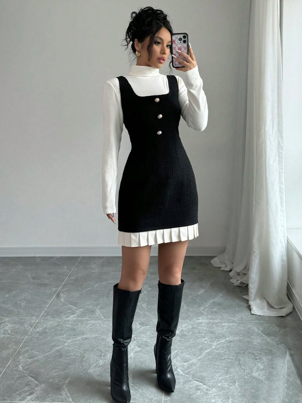Mujer con vestido mini negro con botones frontales y bajo plisado blanco.
