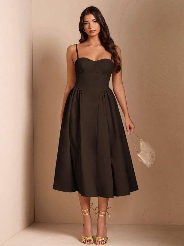 Vista de la falda amplia de un vestido midi café y tacones dorados de tiras.