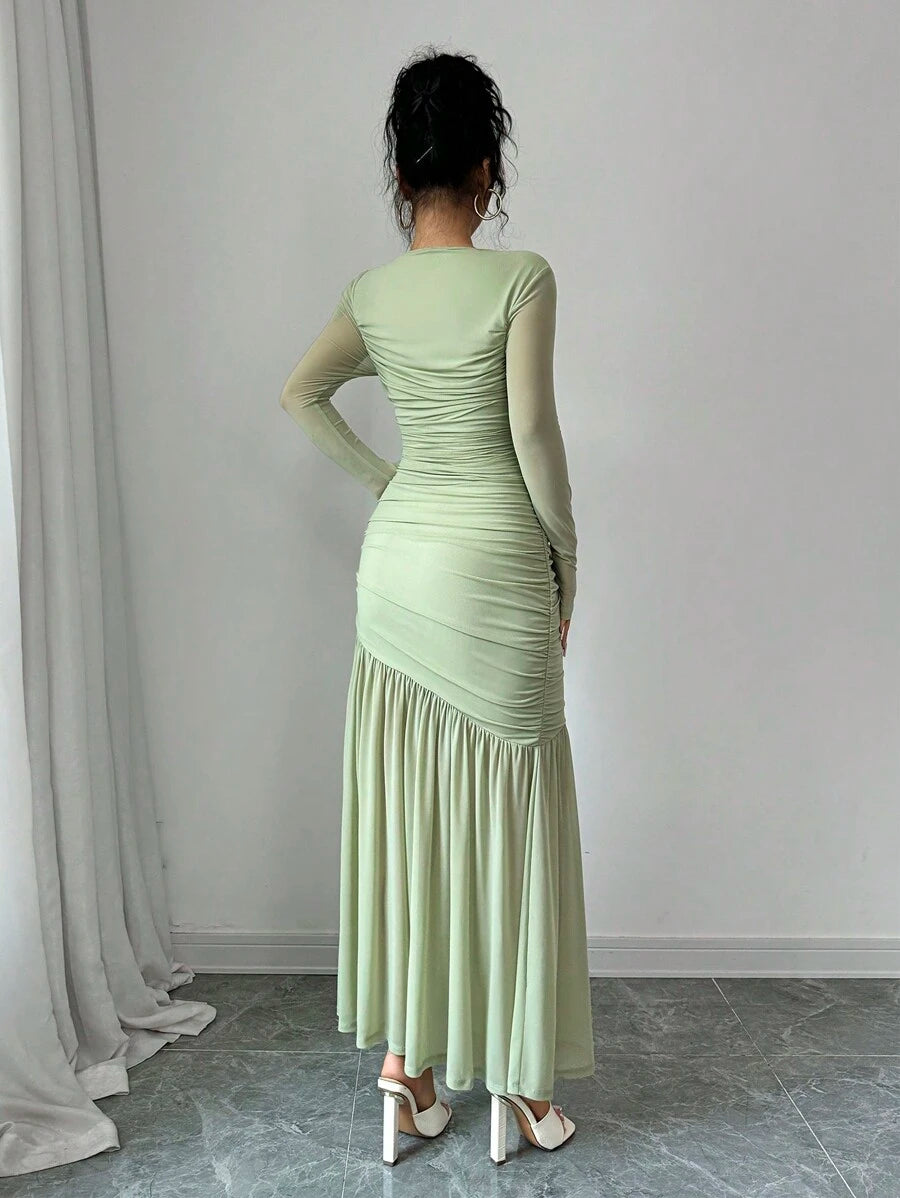 Mujer modelando un vestido largo elegante de color verde menta con fruncido en el cuerpo y mangas largas.