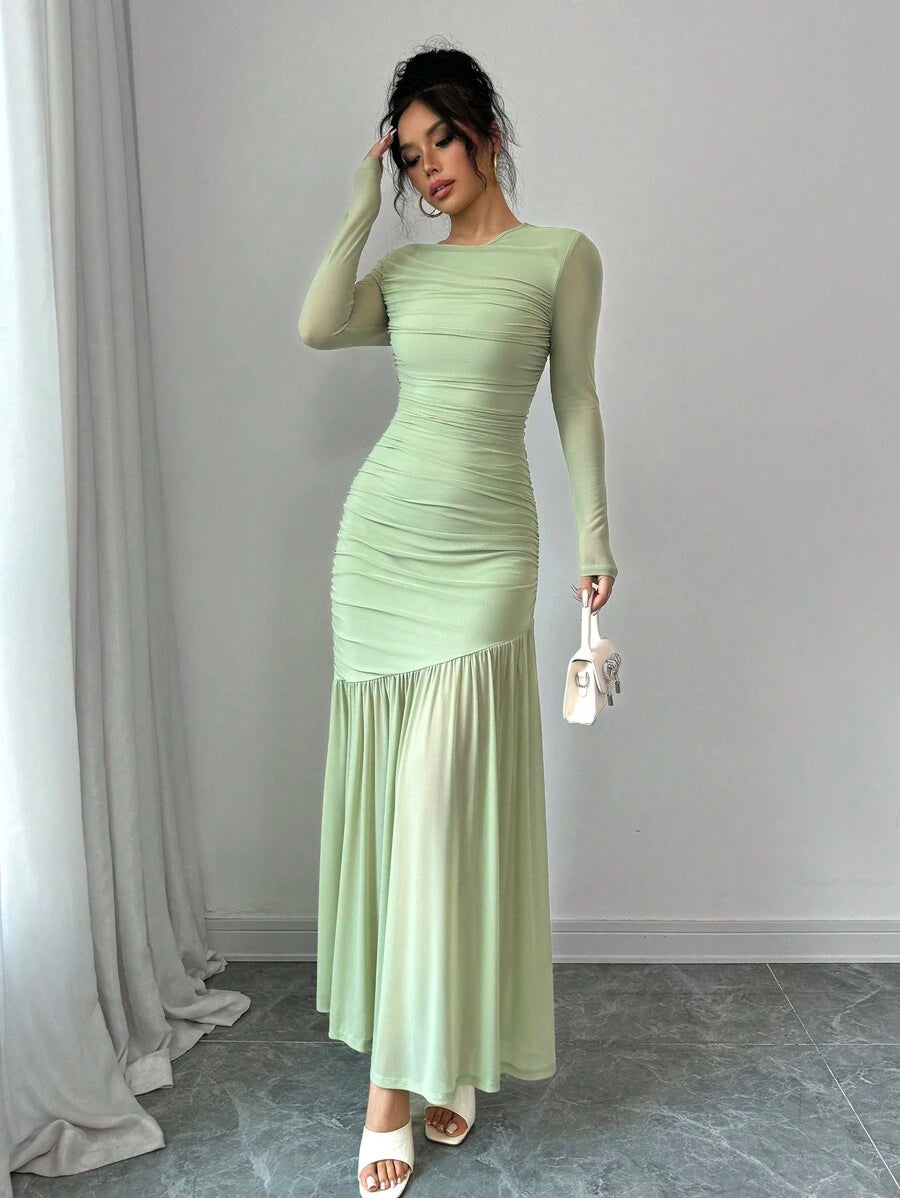 Mujer modelando un vestido largo elegante de color verde menta con fruncido en el cuerpo y mangas largas.