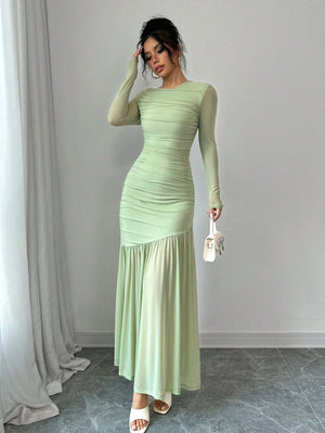 Mujer modelando un vestido largo elegante de color verde menta con fruncido en el cuerpo y mangas largas.