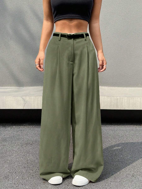 Primer plano del bajo acampanado de un pantalón fluido verde olivo combinado con zapatillas blancas.